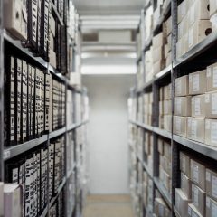 云明日方舟内容审核陈牧正在整理来源登记表的画面，桌上摞着标注了日期的资料夹，暖色台灯照亮记录本